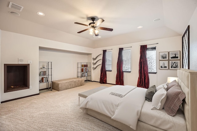 bedroom featuring light carpet, ceiling fan, and a raised ceiling