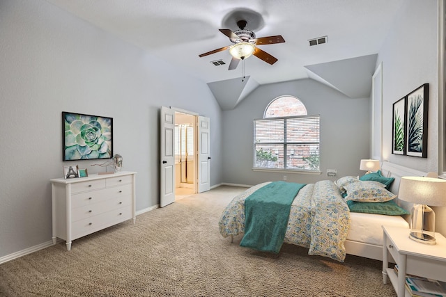 bedroom with ceiling fan, ensuite bath, light colored carpet, and lofted ceiling