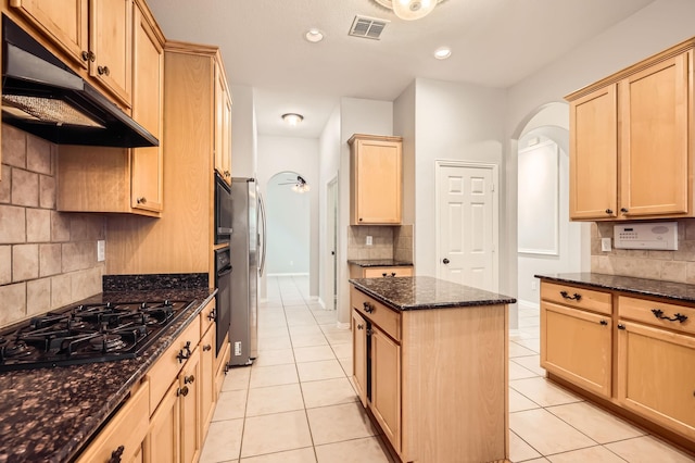 kitchen with dark stone counters, black appliances, light brown cabinetry, and a kitchen island