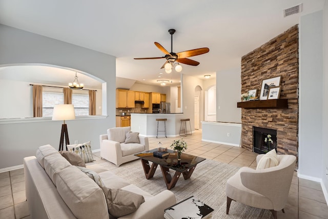 tiled living room featuring ceiling fan and a stone fireplace