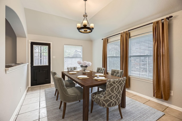 tiled dining room with vaulted ceiling and an inviting chandelier