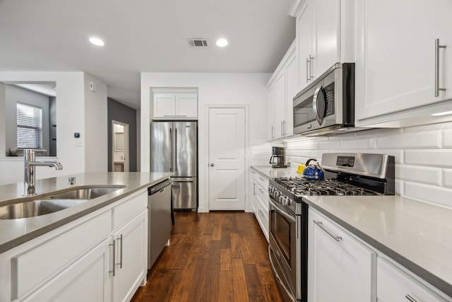 kitchen with dark wood-type flooring, sink, white cabinetry, appliances with stainless steel finishes, and backsplash