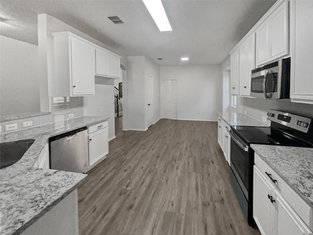 kitchen with sink, appliances with stainless steel finishes, light stone countertops, hardwood / wood-style floors, and white cabinets