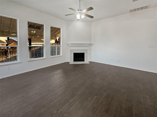 unfurnished living room with dark hardwood / wood-style flooring, a tile fireplace, and ceiling fan