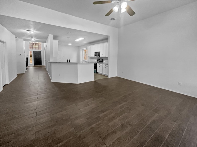 unfurnished living room featuring dark wood-type flooring and ceiling fan