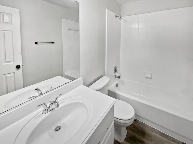 full bathroom featuring hardwood / wood-style flooring, washtub / shower combination, vanity, and toilet