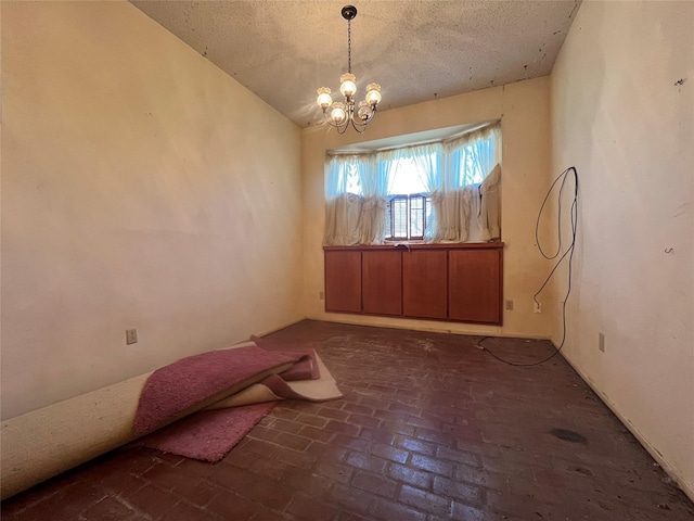 spare room featuring lofted ceiling, a notable chandelier, and a textured ceiling