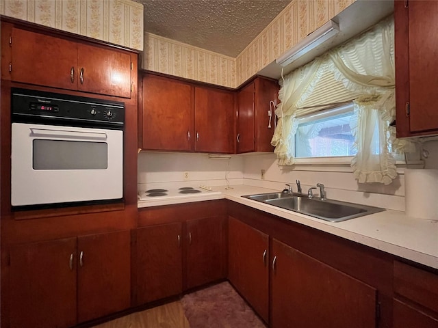 kitchen with sink, white appliances, and a textured ceiling