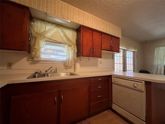 kitchen with white dishwasher, kitchen peninsula, sink, and a textured ceiling