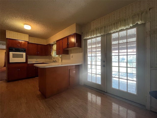 kitchen with oven, kitchen peninsula, a textured ceiling, and french doors