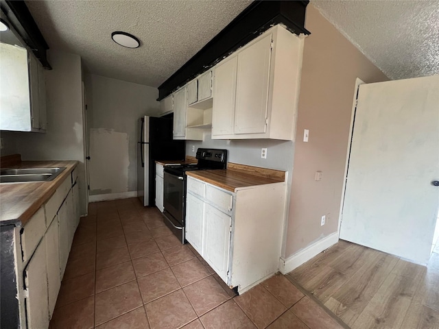 kitchen featuring sink, black electric range, a textured ceiling, and white cabinets