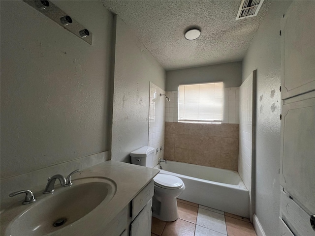 full bathroom featuring tile patterned flooring, tiled shower / bath combo, vanity, a textured ceiling, and toilet