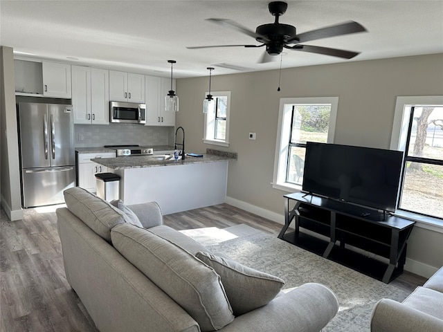 living room with sink, light hardwood / wood-style flooring, and ceiling fan