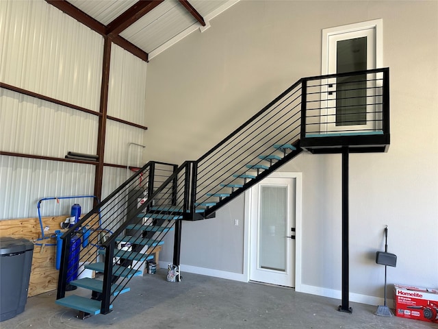 stairway featuring lofted ceiling and concrete flooring