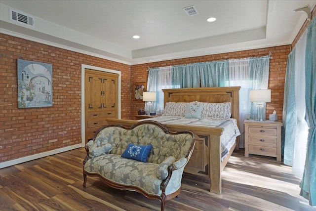 bedroom with brick wall and dark wood-type flooring