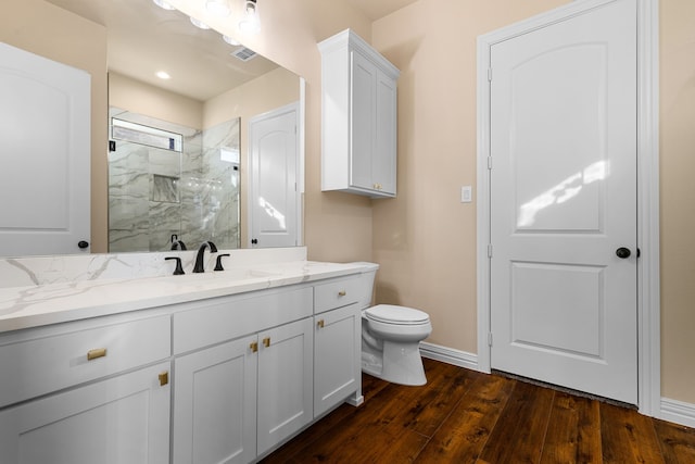 bathroom with vanity, hardwood / wood-style floors, toilet, and a tile shower