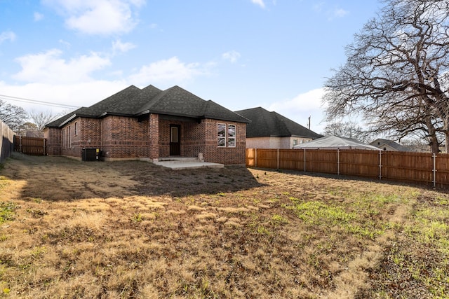 rear view of house featuring a patio, central AC unit, and a lawn