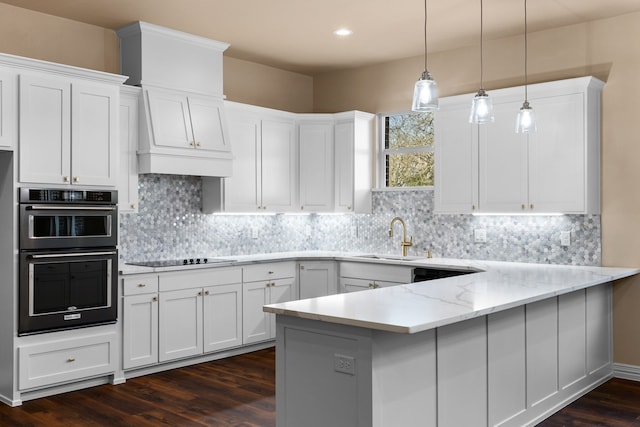 kitchen featuring light stone counters, sink, kitchen peninsula, and white cabinets