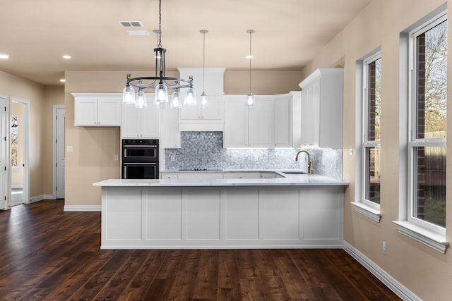 kitchen with white cabinetry, decorative light fixtures, kitchen peninsula, and sink