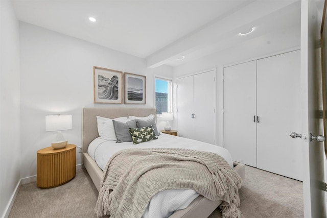 bedroom featuring light carpet and two closets