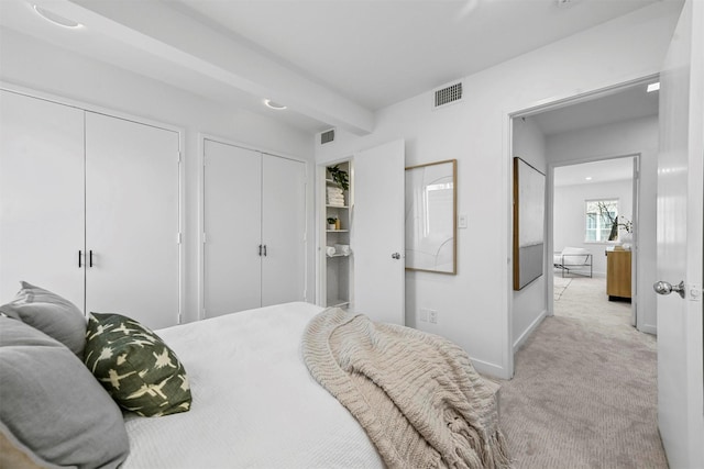 carpeted bedroom featuring two closets and beam ceiling