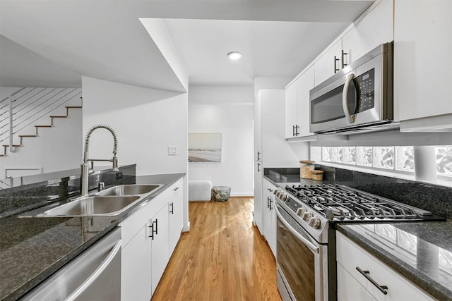 kitchen featuring white cabinetry, appliances with stainless steel finishes, dark stone countertops, and light hardwood / wood-style floors