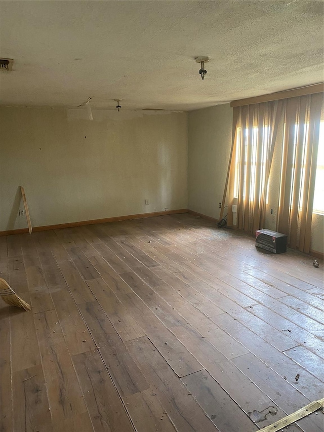 empty room featuring wood-type flooring and a textured ceiling