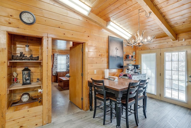 dining room featuring an inviting chandelier, lofted ceiling, wooden walls, and light hardwood / wood-style flooring