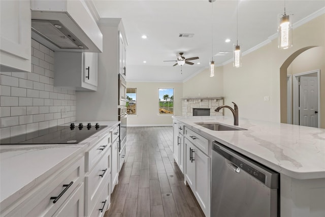 kitchen featuring white cabinetry, hanging light fixtures, appliances with stainless steel finishes, an island with sink, and custom range hood