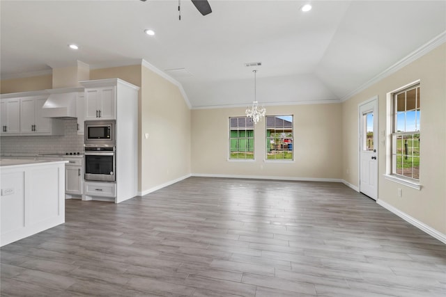 kitchen featuring lofted ceiling, custom range hood, stainless steel appliances, decorative backsplash, and white cabinets