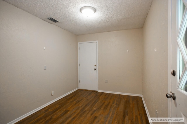 spare room featuring dark hardwood / wood-style flooring and a textured ceiling