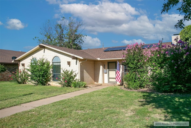 single story home featuring a front yard and solar panels