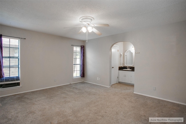 carpeted spare room featuring a healthy amount of sunlight, a textured ceiling, and ceiling fan