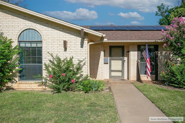 entrance to property with solar panels and a lawn