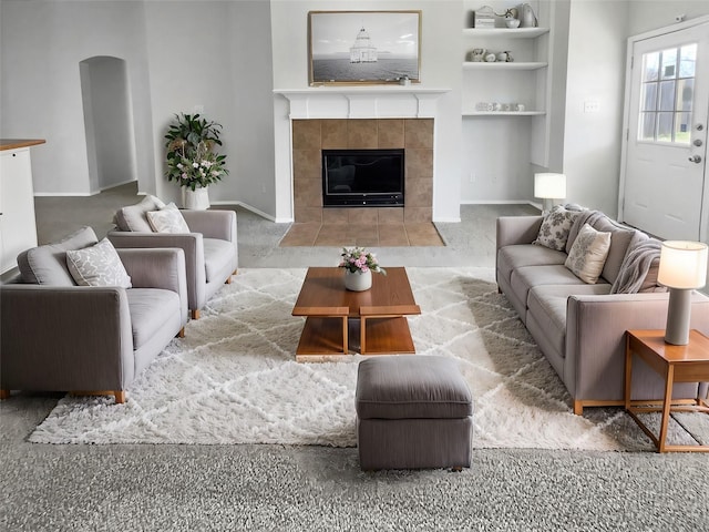 carpeted living room with built in shelves and a fireplace