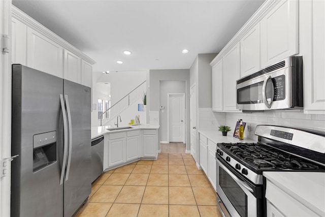 kitchen with light tile patterned floors, sink, appliances with stainless steel finishes, white cabinetry, and decorative backsplash