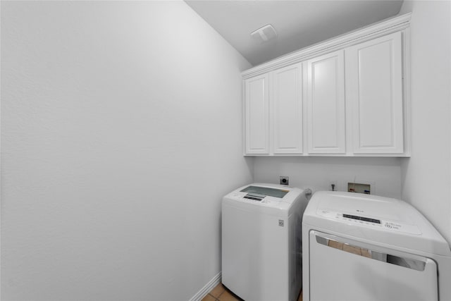 laundry room featuring cabinets, washing machine and dryer, and light tile patterned floors