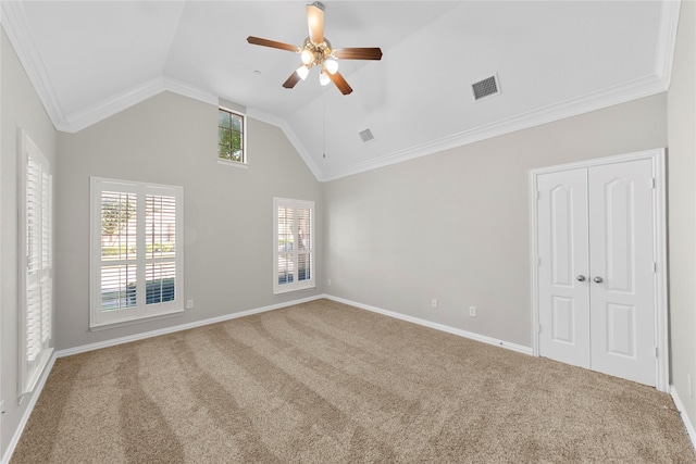 empty room featuring crown molding, vaulted ceiling, ceiling fan, and carpet