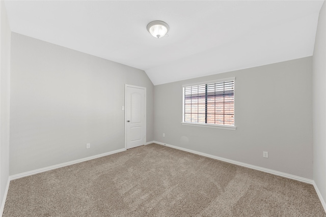 carpeted empty room featuring lofted ceiling