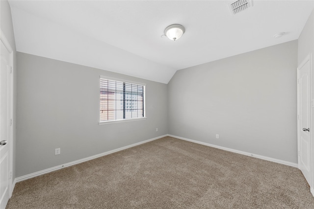 spare room featuring vaulted ceiling and carpet floors