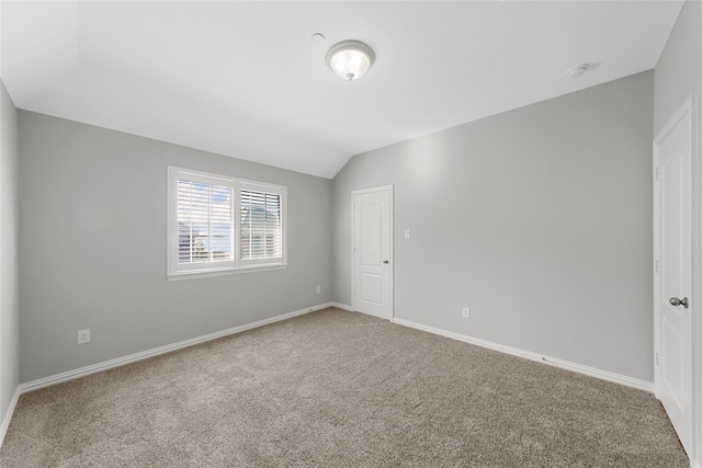 carpeted empty room with lofted ceiling