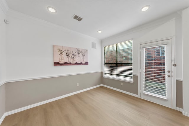 empty room with ornamental molding and light wood-type flooring