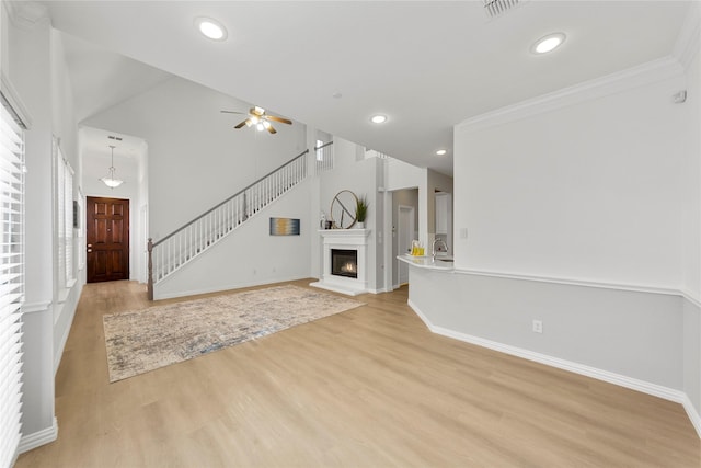 unfurnished living room with ornamental molding, ceiling fan, and light hardwood / wood-style floors