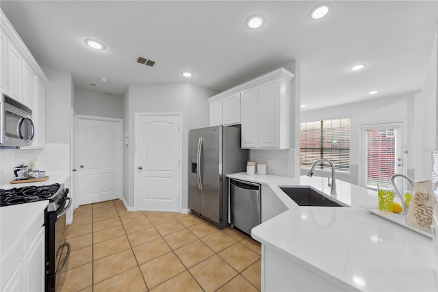 kitchen featuring light tile patterned flooring, sink, appliances with stainless steel finishes, white cabinets, and backsplash