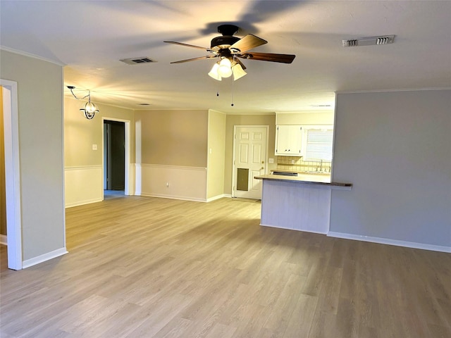 unfurnished living room featuring sink, ornamental molding, light hardwood / wood-style floors, and ceiling fan