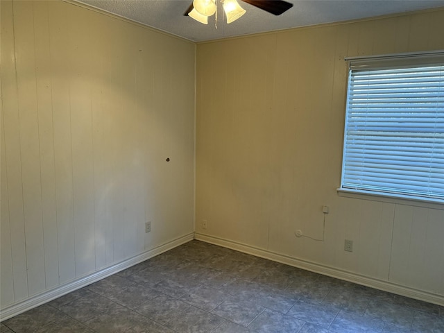 unfurnished room featuring ceiling fan and wood walls