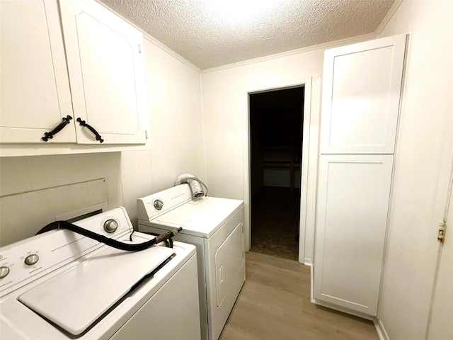 washroom with independent washer and dryer, light hardwood / wood-style floors, cabinets, and a textured ceiling