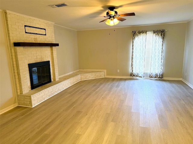 unfurnished living room with hardwood / wood-style flooring, ornamental molding, ceiling fan, and a fireplace