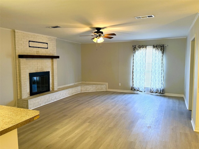 unfurnished living room with crown molding, ceiling fan, a fireplace, and hardwood / wood-style floors