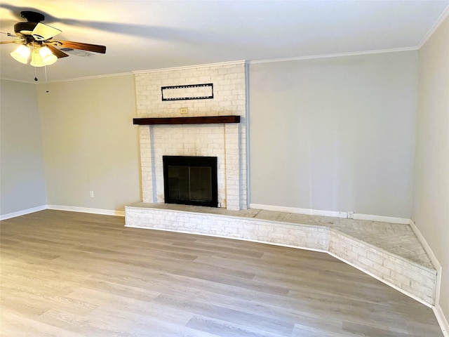 unfurnished living room featuring hardwood / wood-style flooring, ornamental molding, ceiling fan, and a fireplace